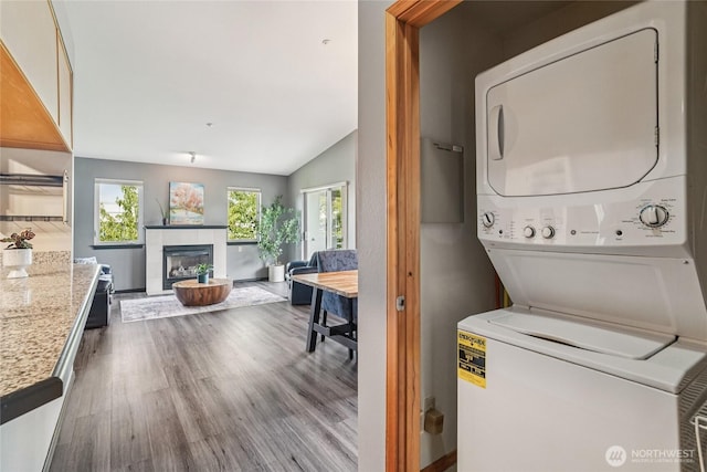 1707 NW 59th St Unit 302, Seattle, WA 98107 - washroom featuring stacked washing machine and dryer, wood finished floors, and a tile fireplace