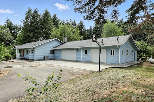 116 Noble Rd, Winlock, WA 98596 - rear view of house with driveway, an attached garage, view of scattered trees, and a chimney
