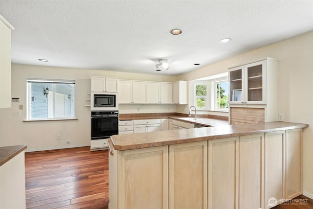 116 Noble Rd, Winlock, WA 98596 - kitchen featuring oven, built in microwave, a peninsula, glass insert cabinets, and wood finished floors