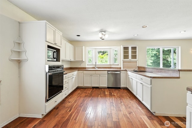 116 Noble Rd, Winlock, WA 98596 - kitchen with black oven, dishwasher, built in microwave, dark wood-style flooring, and white cabinetry