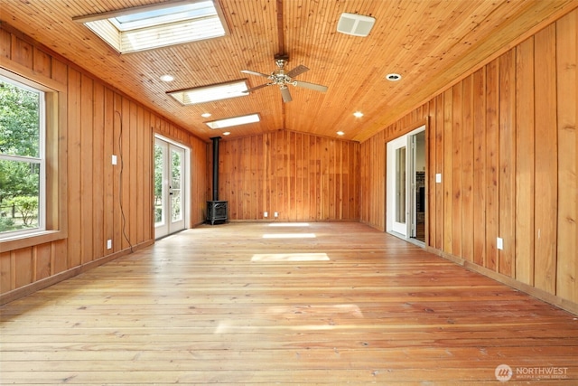 116 Noble Rd, Winlock, WA 98596 - unfurnished room with a skylight, a wood stove, light wood-type flooring, vaulted ceiling, and wood walls