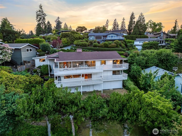 818 179th Pl NE, Bellevue, WA 98008 - rear view of house with a balcony, view of wooded area, and a chimney