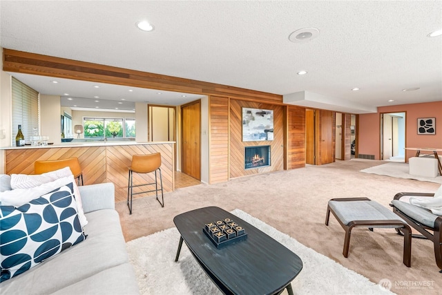 818 179th Pl NE, Bellevue, WA 98008 - living room with light colored carpet, wooden walls, a textured ceiling, recessed lighting, and a warm lit fireplace