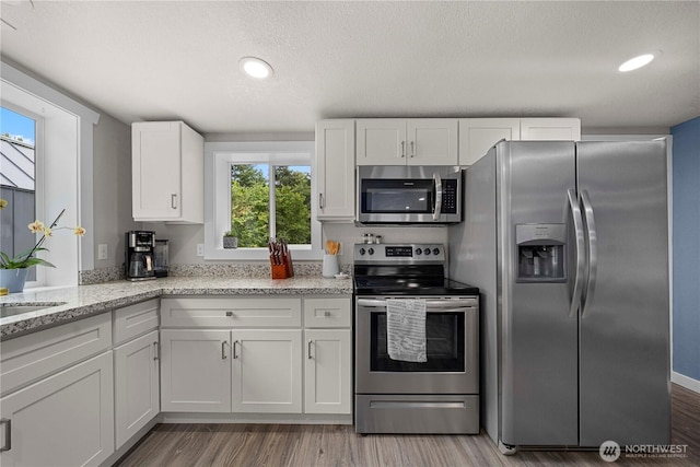 4415 Waller Rd E, Tacoma, WA 98443 - kitchen featuring stainless steel appliances, white cabinetry, light wood-style floors, light stone countertops, and recessed lighting