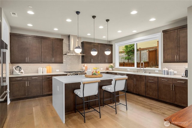 10259 133rd Ct NE, Redmond, WA 98033 - kitchen featuring wall chimney exhaust hood, light wood-type flooring, a kitchen island, a breakfast bar area, and recessed lighting