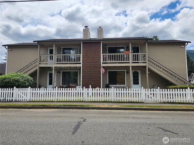 133 W 4th St, North Bend, WA 98045 - view of front of home featuring a chimney, stairway, a fenced front yard, and a balcony