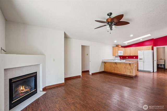 87 Chickadee Dr, Kelso, WA 98626 - unfurnished living room featuring ceiling fan, lofted ceiling, dark wood-style flooring, a tiled fireplace, and recessed lighting