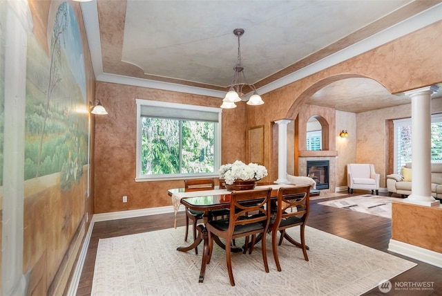 1122 36th Ave NE, Olympia, WA 98506 - dining area featuring decorative columns, arched walkways, a fireplace, wood finished floors, and a raised ceiling