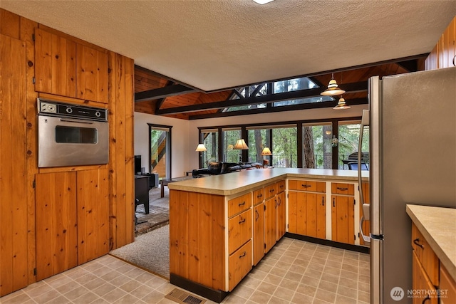 24302 Saddle St, Leavenworth, WA 98826 - kitchen with appliances with stainless steel finishes, light countertops, a peninsula, a textured ceiling, and beamed ceiling