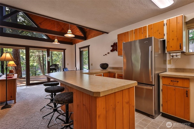 24302 Saddle St, Leavenworth, WA 98826 - kitchen with freestanding refrigerator, light countertops, a peninsula, and a kitchen bar