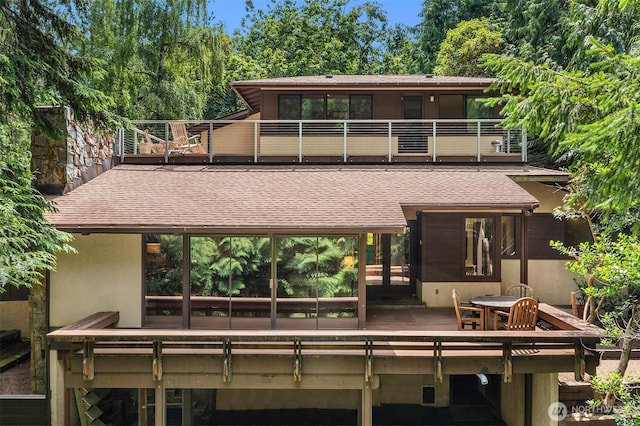 back of property with roof with shingles and a balcony