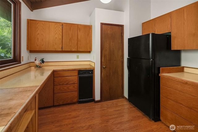 kitchen featuring freestanding refrigerator, light wood finished floors, light countertops, and brown cabinets