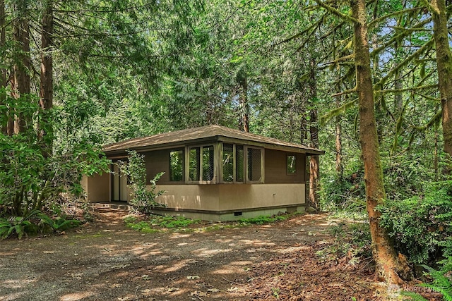 view of front of home with crawl space and a forest view