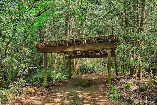 view of home's community with a wooded view, a carport, and driveway