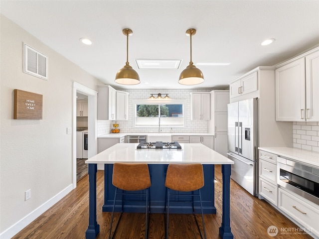 724 6th Ave SW, Puyallup, WA 98371 - kitchen with appliances with stainless steel finishes, backsplash, a kitchen bar, a kitchen island, and recessed lighting
