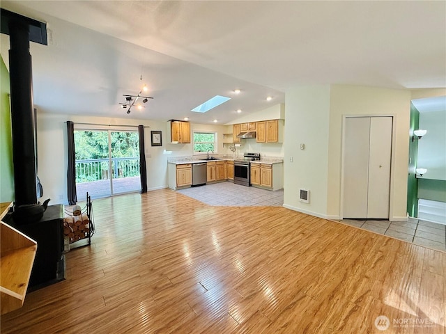 11422 Leschi Cir, Anderson Island, WA 98303 - living room featuring light wood finished floors, vaulted ceiling, a skylight, a wood stove, and recessed lighting