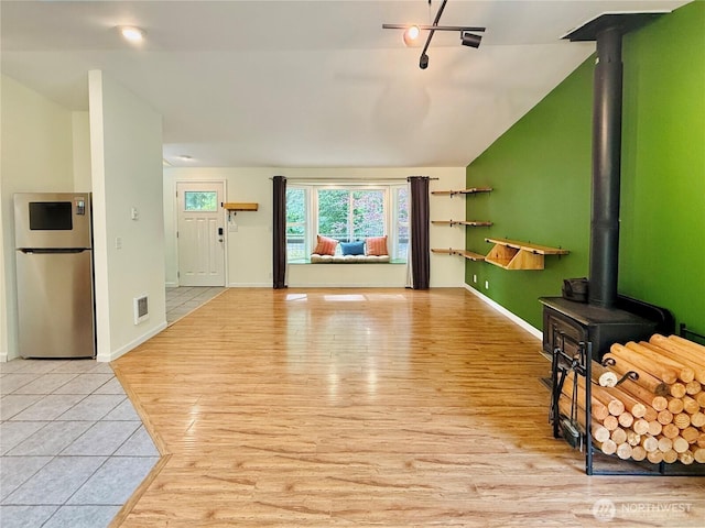 11422 Leschi Cir, Anderson Island, WA 98303 - unfurnished living room with a wood stove, light wood-type flooring, and lofted ceiling