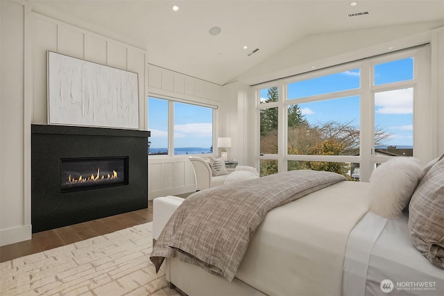 1918 94th Ave NE, Clyde Hill, WA 98004 - bedroom featuring wood finished floors, vaulted ceiling, a glass covered fireplace, recessed lighting, and a water view