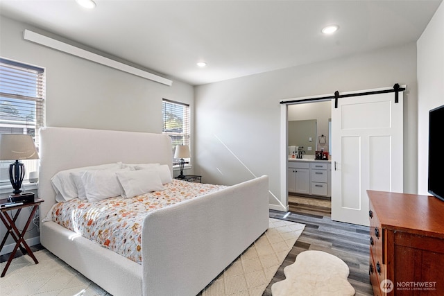 1575 Kingsley Ave, Blaine, WA 98230 - bedroom featuring a barn door, light wood-type flooring, recessed lighting, and ensuite bath