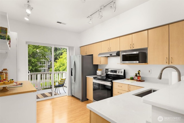 18223 NE 95th Way Unit 102, Redmond, WA 98052 - kitchen with stainless steel appliances, under cabinet range hood, track lighting, light brown cabinetry, and light countertops