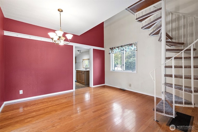 406 4th St NE, Puyallup, WA 98372 - empty room with a chandelier, wood finished floors, stairs, and lofted ceiling