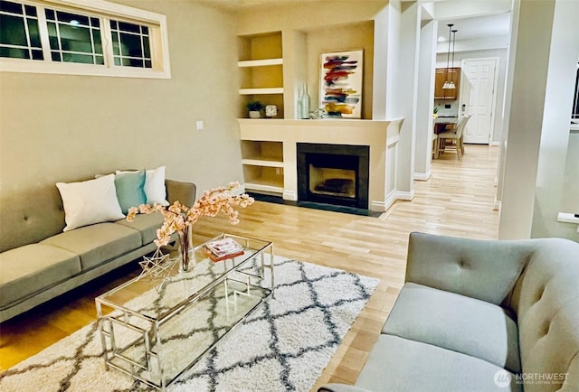 6802 156th Pl NE, Redmond, WA 98052 - living area featuring built in shelves, wood finished floors, and a fireplace with flush hearth