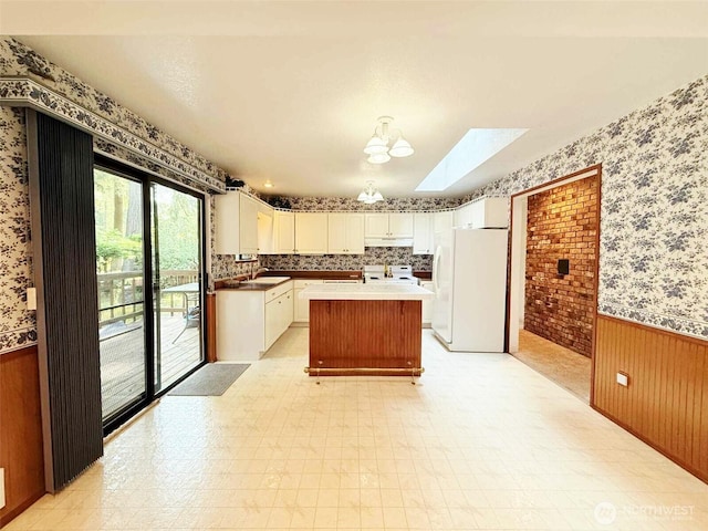 4905 US Highway 12, Elma, WA 98541 - kitchen featuring freestanding refrigerator, wallpapered walls, a wainscoted wall, stove, and under cabinet range hood