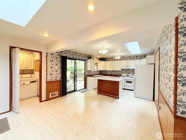 4905 US Highway 12, Elma, WA 98541 - kitchen featuring a skylight, wallpapered walls, washer / dryer, white appliances, and wainscoting