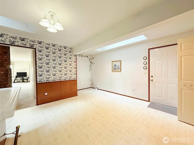 4905 US Highway 12, Elma, WA 98541 - unfurnished living room featuring a wainscoted wall, wallpapered walls, and a skylight