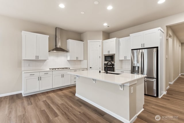 5801 SW Thornhill Ave SW Unit 323, Port Orchard, WA 98367 - kitchen featuring wall chimney exhaust hood, stainless steel appliances, a kitchen island with sink, recessed lighting, and white cabinets
