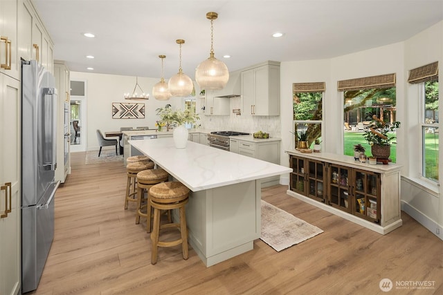 43936 SE 127th Pl, North Bend, WA 98045 - kitchen with high end appliances, light wood-style flooring, a kitchen bar, tasteful backsplash, and a kitchen island