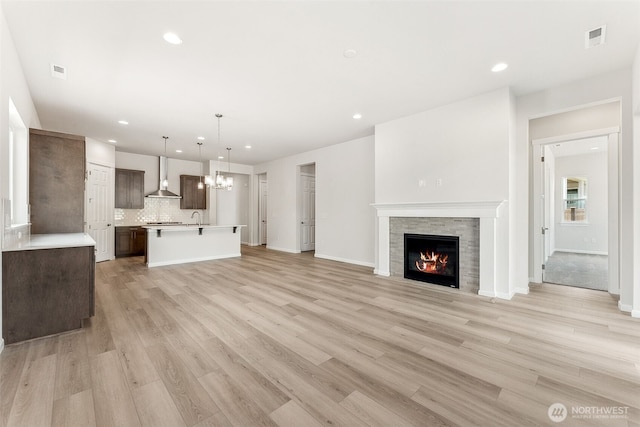 5781 SW Thornhill Ave SW Unit 324, Port Orchard, WA 98367 - unfurnished living room with a lit fireplace, light wood-style flooring, recessed lighting, and a chandelier
