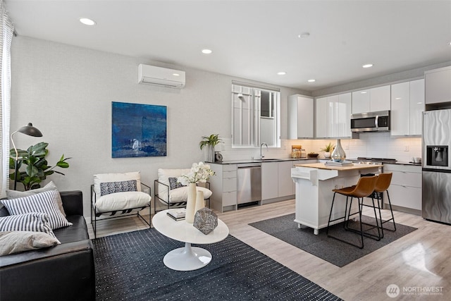 2521 29th Ave S Unit C, Seattle, WA 98144 - kitchen with appliances with stainless steel finishes, an AC wall unit, light wood-style flooring, a breakfast bar, and recessed lighting