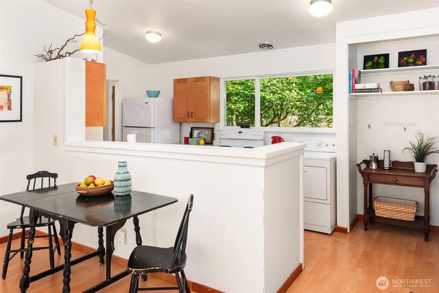 9922 SW 206th Ct, Vashon, WA 98070 - kitchen with freestanding refrigerator, light wood-style floors, brown cabinetry, a peninsula, and washer / clothes dryer