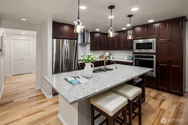 12810 SE 22nd Pl, Bellevue, WA 98005 - kitchen featuring stainless steel appliances, wall chimney range hood, light wood finished floors, dark brown cabinets, and recessed lighting