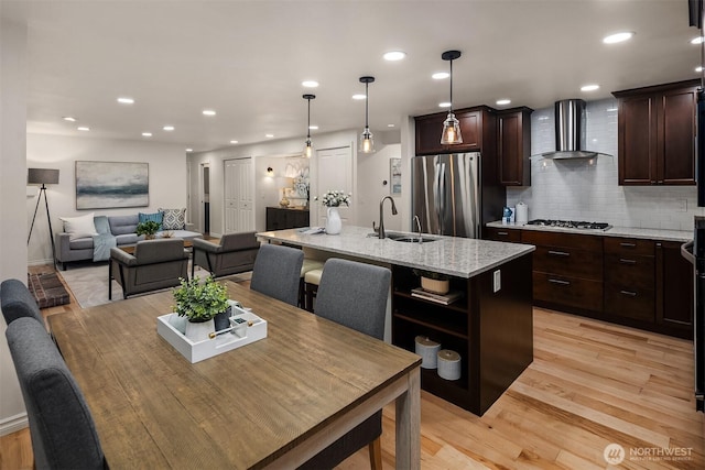 12810 SE 22nd Pl, Bellevue, WA 98005 - kitchen with wall chimney exhaust hood, stainless steel appliances, a kitchen island with sink, backsplash, and dark brown cabinetry