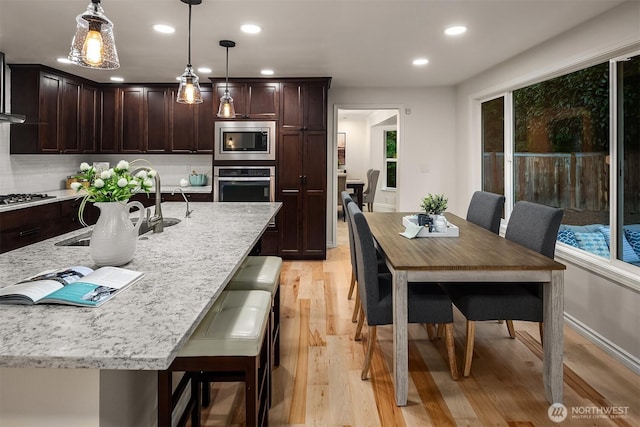 12810 SE 22nd Pl, Bellevue, WA 98005 - kitchen with stainless steel appliances, recessed lighting, light wood-style floors, dark brown cabinetry, and decorative light fixtures