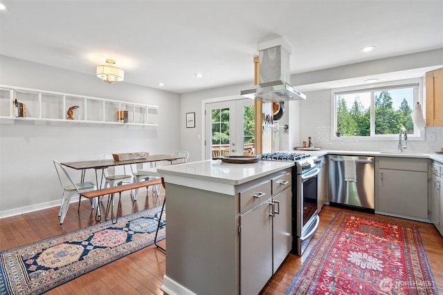 6511 Canyon Ct SW, Olympia, WA 98512 - kitchen with appliances with stainless steel finishes, island range hood, a peninsula, gray cabinets, and backsplash