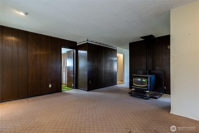 913 Woodlawn, Walla Walla, WA 99362 - unfurnished living room featuring carpet, a wood stove, wooden walls, and a textured ceiling