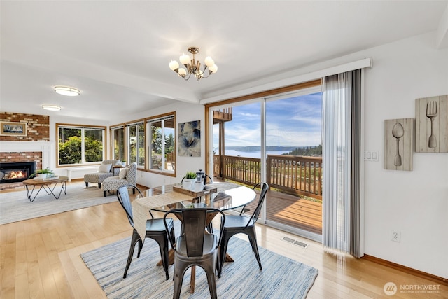 14007 65th Pl W, Edmonds, WA 98026 - dining space featuring a chandelier, light wood finished floors, a brick fireplace, and beam ceiling
