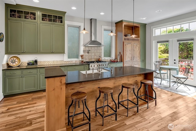 2611 9th Ave W, Seattle, WA 98119 - kitchen with wall chimney exhaust hood, green cabinets, light wood finished floors, dark countertops, and recessed lighting