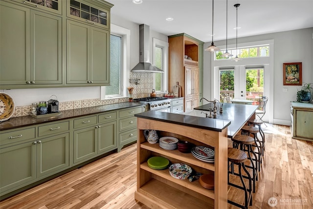 2611 9th Ave W, Seattle, WA 98119 - kitchen with green cabinetry, wall chimney exhaust hood, open shelves, dark countertops, and light wood-type flooring