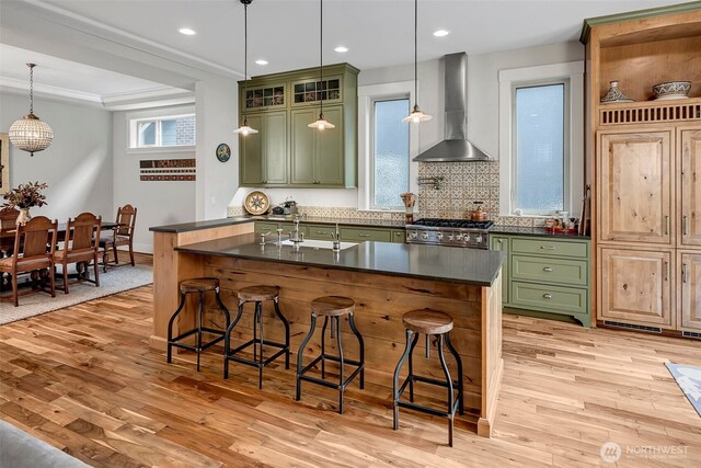 2611 9th Ave W, Seattle, WA 98119 - kitchen with green cabinets, wall chimney range hood, light wood-style flooring, dark countertops, and stainless steel range