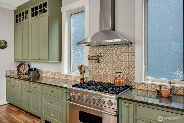 2611 9th Ave W, Seattle, WA 98119 - kitchen featuring green cabinets, wall chimney exhaust hood, high end stainless steel range oven, tasteful backsplash, and dark countertops