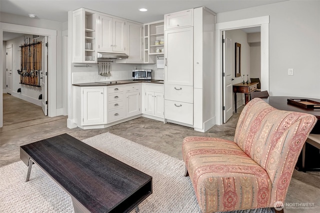 2611 9th Ave W, Seattle, WA 98119 - kitchen featuring open shelves, stainless steel microwave, dark countertops, under cabinet range hood, and white cabinetry