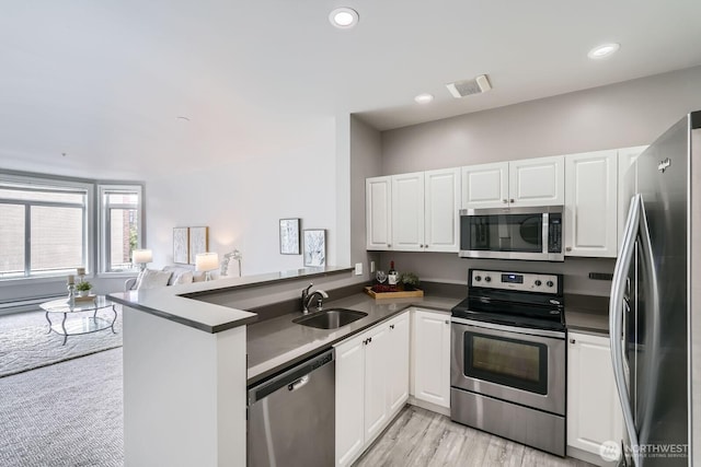 2414 1st Ave Unit 519, Seattle, WA 98121 - kitchen featuring appliances with stainless steel finishes, dark countertops, a peninsula, white cabinetry, and open floor plan