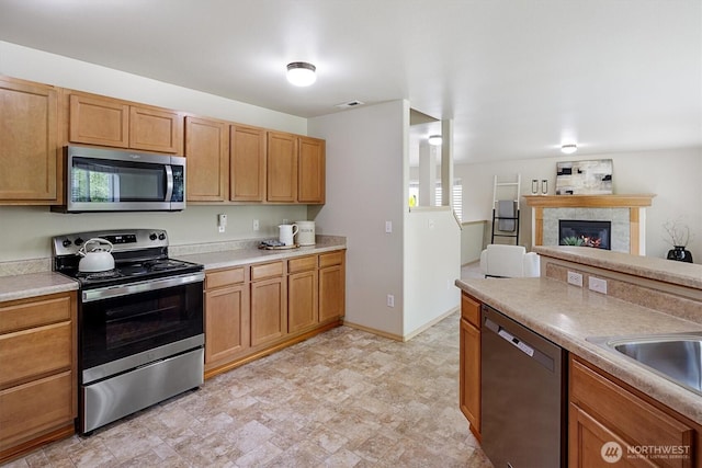 33036 42nd Ave S, Federal Way, WA 98001 - kitchen featuring appliances with stainless steel finishes, light countertops, a tile fireplace, open floor plan, and stone finish floors