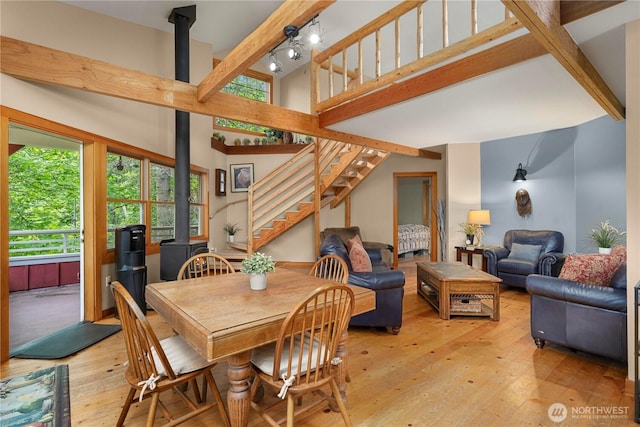 36 Seven Sisters Rd, Port Ludlow, WA 98365 - dining room featuring beam ceiling, light wood finished floors, a wood stove, stairs, and a towering ceiling