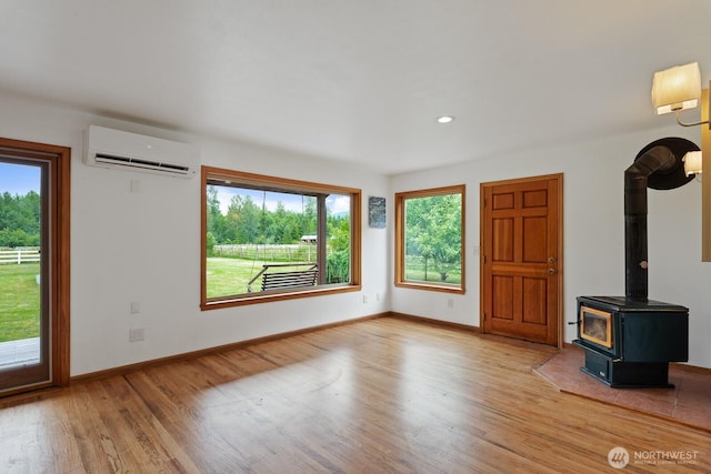 6373 Eastwood Rd, Deming, WA 98244 - unfurnished living room with a wall mounted air conditioner, light wood-type flooring, a wood stove, and recessed lighting