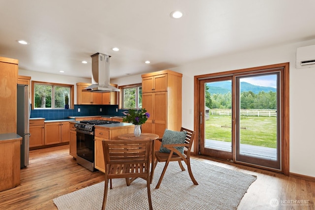 6373 Eastwood Rd, Deming, WA 98244 - kitchen with stainless steel appliances, island exhaust hood, backsplash, a wall mounted air conditioner, and light wood finished floors